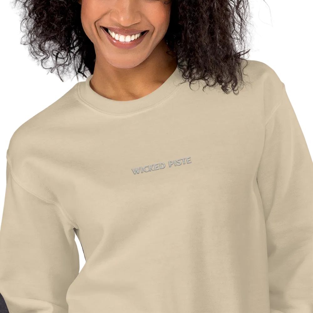 A close-up of a smiling woman wearing a light beige crewneck sweatshirt with a small gold arched text graphic on the left chest reading 'HE RESTORES MY SOUL'.